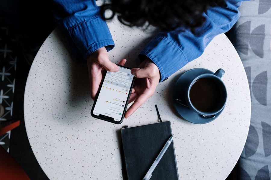 Person checking messages on a smartphone beside a notebook